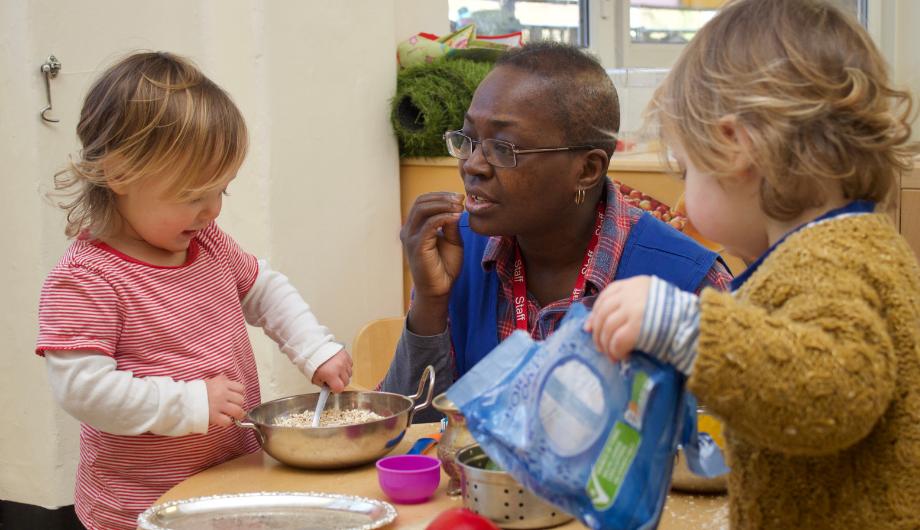 Staff using makaton/sign language with toddler in the home corner